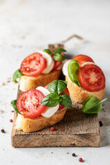 Italian bruschetta with tomatoes, mozzarella and basil on rustic wooden board