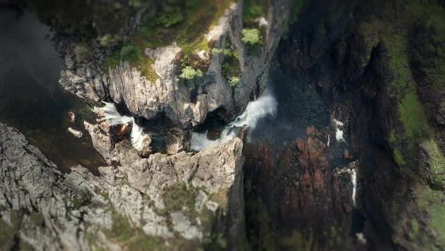Aerial view of the massive waterfall falling into a deep rocky canyon. Water dust rises high in the air. Slow-motion.
