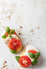 Italian bruschetta with tomatoes, mozzarella and basil on textured background top view, text space