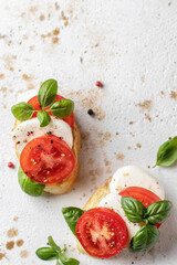 Fototapeta na wymiar Italian bruschetta with tomatoes, mozzarella and basil on textured background close up top view, text space