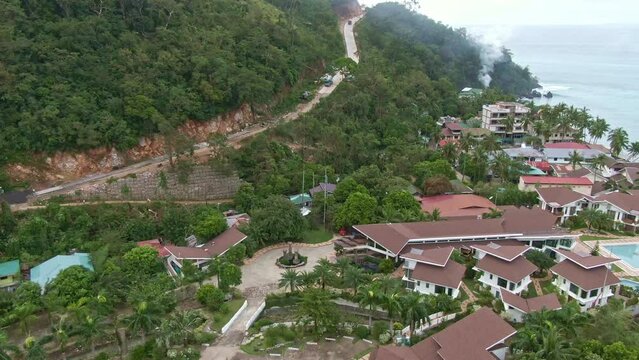 Side aerial drone shot of long highway hillside, landscape of the resorts and houses near at the beach