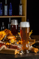 Glass of beer on bar counter. Jugs, mugs, pints of brew beverage, ale, cider on wooden table in...