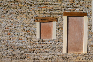 Close-up of an old brick and stone wall with walled door and window, Italy