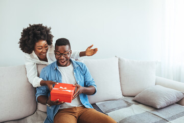 Young couple with gift box hugging at home. Valentine's Day concept. Happy couple in love with. A...