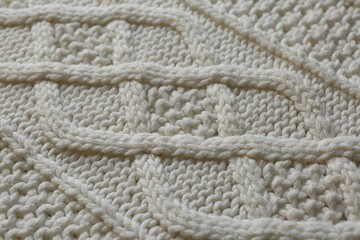 Fototapeta na wymiar White knitted fabric with beautiful pattern as background, closeup