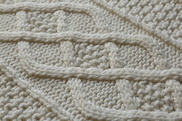 White knitted fabric with beautiful pattern as background, closeup