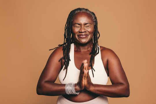 Cheerful black woman meditating in a studio