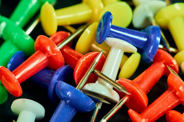 Buttons for attaching paper to a blackboard or wall are photographed in close-up, a sharp metal tip...