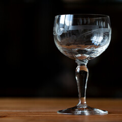 antique transparent glass wine glass on a black background. crystal glass with engraving. glass close-up