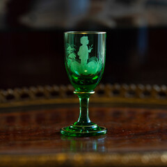 green glass wineglass in luxury interior. green glass with engraving close-up. bohemian glass closeup