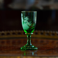 green glass wineglass in luxury interior. green glass with engraving close-up. bohemian glass closeup