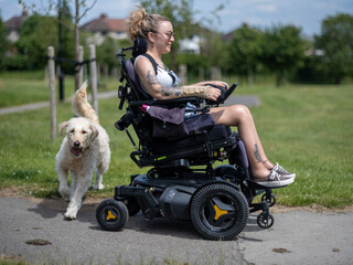 Woman in electric wheelchair going on walk with dog