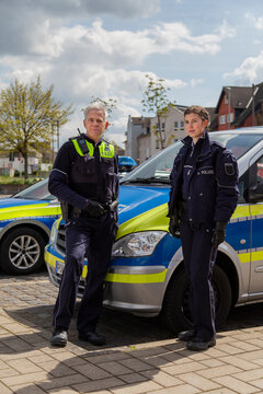 Polizisten stehen vor Streifenwagen