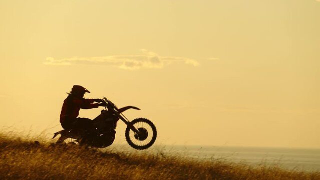 Silhouette of Extreme Motocross Biker jumping motor bike on sunrise background