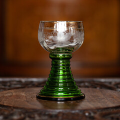 green glass goblet of unusual shape in a luxurious interior. green goblet close-up. bohemian glass closeup