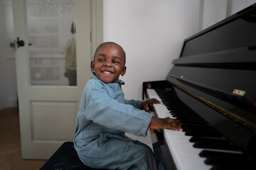 Smiling boy (2-3) playing piano