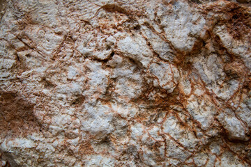White stone with red flecks. Wavy texture and structure of the stone. There are crystalline inclusions on the surface of the drop. The texture of the rock.