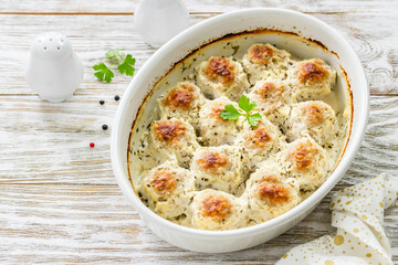 Sour cream meatballs in baking dish on wooden background. Top view, copy space, flat lay.