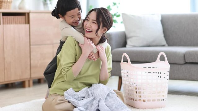 洗濯物を畳む母親に抱きつく女の子