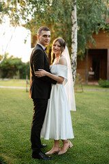 Fototapeta premium young couple the groom in a black suit and the bride in a white short dress