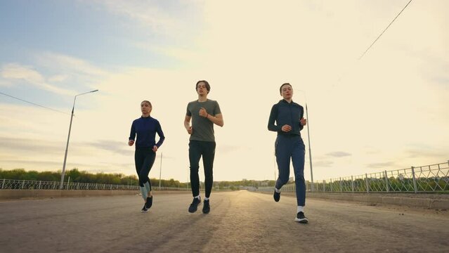 joggers are running in morning outdoors, three young persons are training together, preparing to marathon