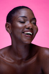 Studio portrait of smiling shirtless woman against pink background