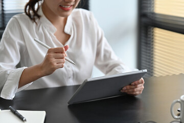 Close up with Businesswoman working in the office checking and analyzing report on digital tablet.