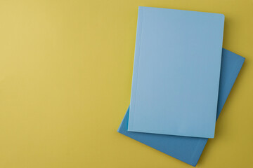 School notebooks of blue color are located on a yellow background. Business notes. Blue-yellow color combination. Top View. Background with place for text. Learning concept. Back to school