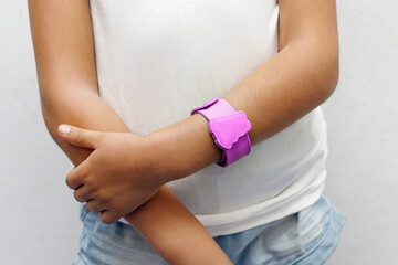 Pink protective bracelet against insect mosquitoes on the hand of a girl close-up