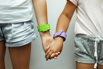 Green and purple protective bracelet against mosquito insects on the hands of girls close-up....