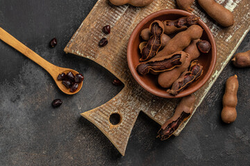 Tropical fruits, Tamarindo beans in shell on a brown butchers block on a dark background, healthy fruit. banner, menu, recipe place for text, top view