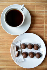 Tea couple on a mat with chocolate bars. A porcelain cup and saucer and tea with sweets.