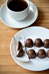 Tea couple on a mat with chocolate bars. A porcelain cup and saucer and tea with sweets.