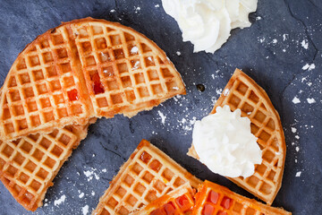 Waffles with syrup and cream on black slate with copy space