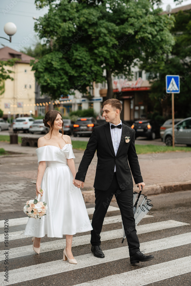 Wall mural young couple bride and groom in a white short dress