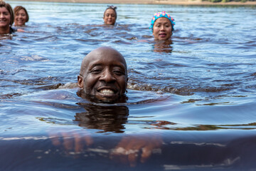 Group of smiling friends swimming in lake, Yorkshire, UK - obrazy, fototapety, plakaty