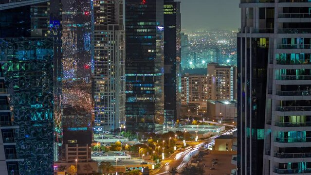 Tall residential buildings at JLT district aerial night timelapse, part of the Dubai multi commodities centre mixed-use district. Traffic between skyscrapers
