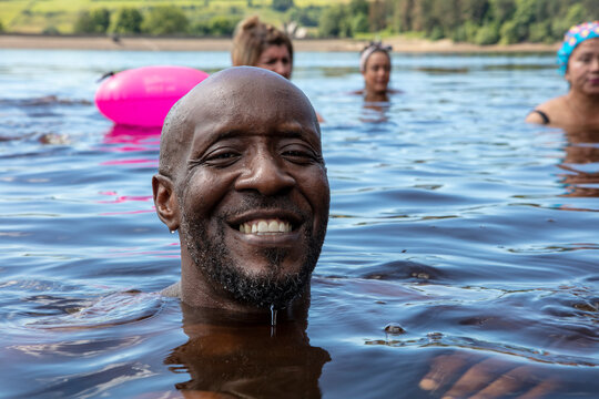 Group Of Smiling Friends Swimming In Lake, Yorkshire, UK