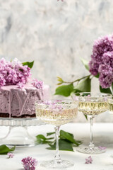 Obraz na płótnie Canvas Delicious prosecco, champagne, wine with berry mousse cake bouquet of purple blooming lilacs, French cuisine, postcard, background