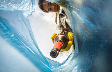 Close-up of a woman hand throwing garbage into a plastic bag. View from inside the bag. The concept...