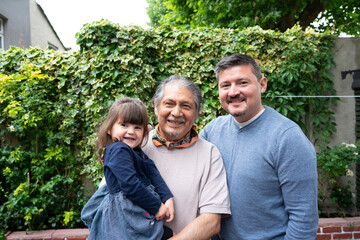 Portrait of smiling senior man with son and granddaughter outdoors