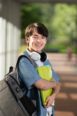 Portrait of cute student boy smiling and looking at camera in a corridor.