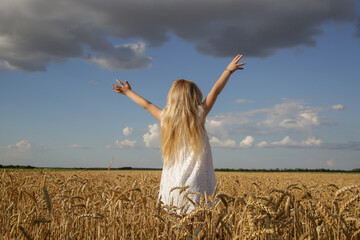 Adorable little girl in white dress in a wheat field