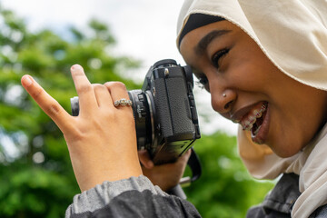 Close-up of smiling young woman wearing hijab photographing with digital camera