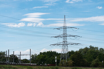 Landscape with power pole and transformer station. Blue sky and forest in the background. Electricity supply for houshoulds and industry.