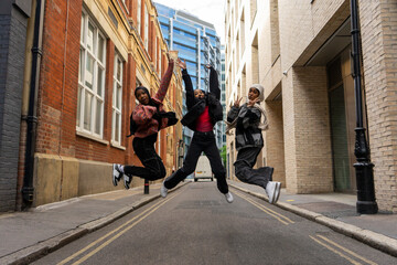 Three young women wearing hijabs jumping in city
