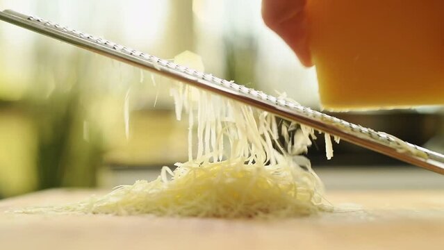 Grating parmesan cheese with a grater in the kitchen.
