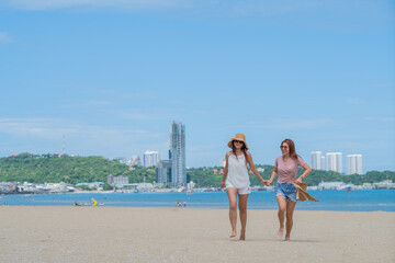 Naklejka premium two women touching hands on the beach, vacation, summer time 