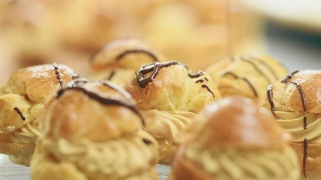 Melted chocolate pouring on profiteroles with coffee and caramel cream.
