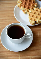 Tea couple with Viennese waffles on a mat. Tea party with waffles. A porcelain cup and saucer on a mat.